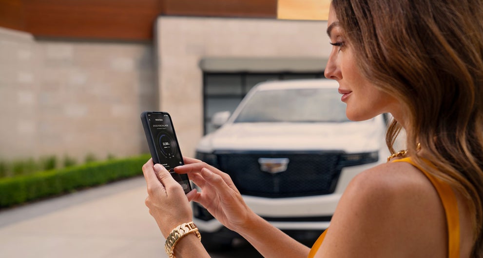 lady checking her mobile with a Cadillac vehicle background | Lynn Layton Cadillac in Decatur AL